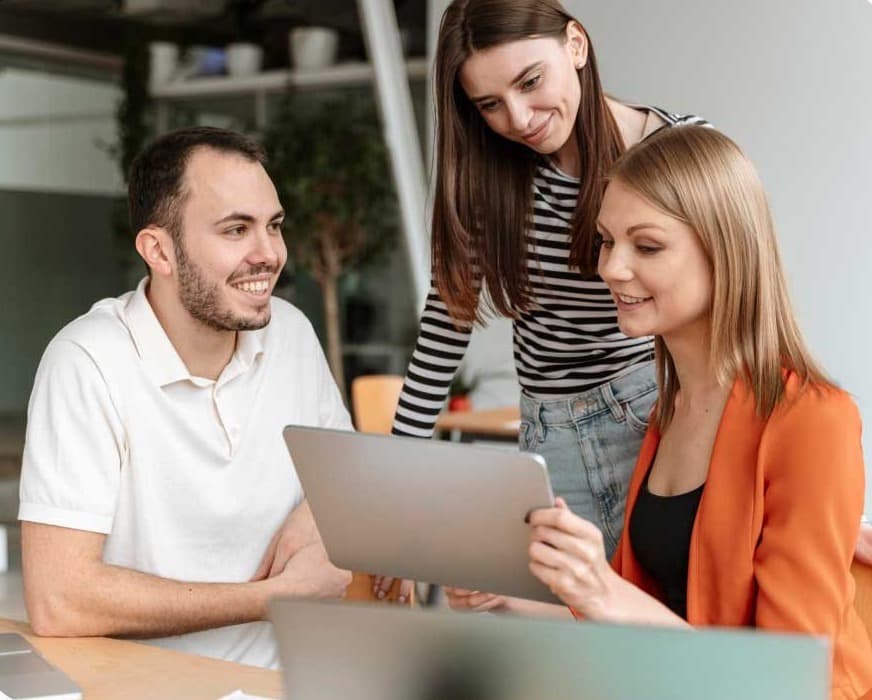 Three colleagues reviewing work together on a laptop